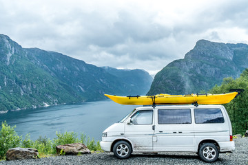 van with canoe standing infront of fjord