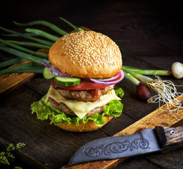 double cheeseburger with vegetables and cheese, white round bun with sesame