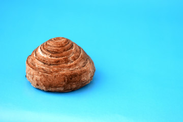 Bun with cinnamon close-up on a light blue background and copy space