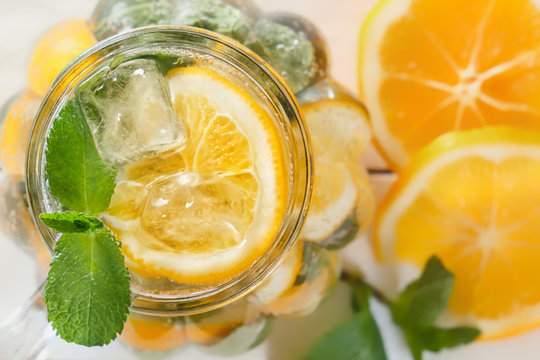 Mason jar of a homemade lemonade with mint and ice, citrus slices on a rustic white wooden background. Close-up. Top view