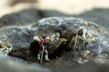 Miniature people, backpackers walking on the stones at beach. Image use for travel Lifestyle adventure vacations concept.
