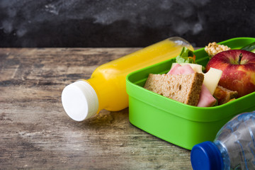 Healthy school lunch box: Sandwich, vegetables, fruit, juice and water on wooden table. Copyspace