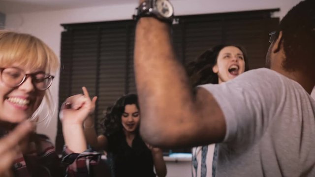 Excited multiethnic young people dance together, celebrating friendship and life at fun casual house party slow motion.