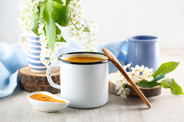 Vitaminic healthy sea buckthorn tea in metal tea cup on the white background. blooming tree branches