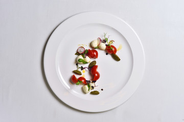 Mozzarella with tomatoes salad on a white plate isolated.