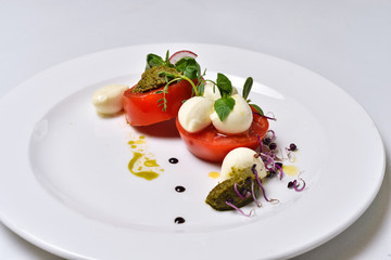 Mozzarella with tomatoes salad on a white plate isolated.