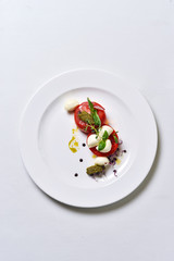 Mozzarella with tomatoes salad on a white plate isolated.