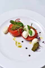 Mozzarella with tomatoes salad on a white plate isolated.