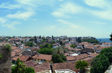 Fototapeta na wymiar Tiled roofs of an old Mediterranean city against a blue sky. Antalya, Turkey