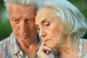 Sad senior couple in autumn park