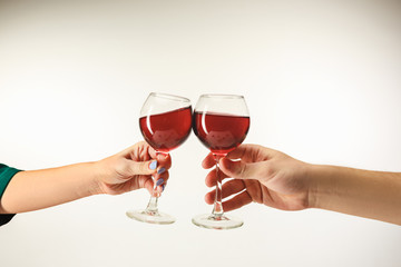 Hands with glasses of red wine, isolated on white