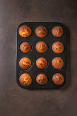 Fresh baked homemade lemon cakes muffins in black teflon baking dish over dark texture background. Top view, space.