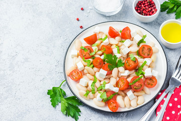 White bean tomato salad on concrete background. Selective focus, space for text.