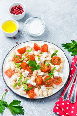 White bean tomato salad on concrete background. Selective focus, space for text.
