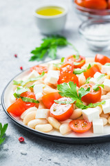 White bean tomato salad on concrete background. Selective focus, space for text.