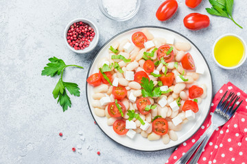 White bean tomato salad on concrete background. Top view, space for text.