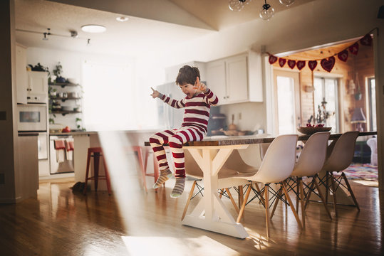 Boy sitting on dining room table singing and dancing
