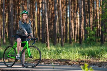 Fototapeta premium Girl on a bicycle in a grey hoodie in the park. Races on a bicycle. Active way of life and playing sports. 