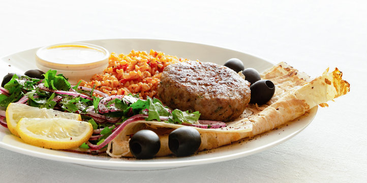 Fried Turkey Meatball With Bulgur Porridge, Flat Bread, Parsley Onion Salad Decorated With Lemon And Olives Served With Adjika Yogurt Based Sauce