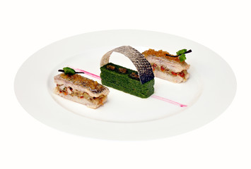 Perch, stuffed eggplant and sun-dried tomatoes, with a sauce of vanilla, lemon confit and a puree of spinach isolated on a white background.