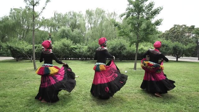 African women are dancing a folk traditional dance on a grass meadow, in traditional costumes with wicker baskets, sunny, trees' background, African costumes, traditions, African culture, tribes