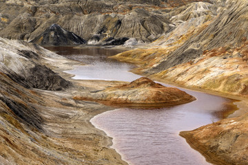 lake with red water with dissolved pyrite salts in the desert landscape of a spent quarry..
