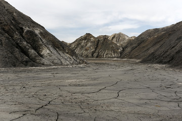 landscape - view from the bottom of a dry desert canyon with a sandy-clay bottom and weathered slopes