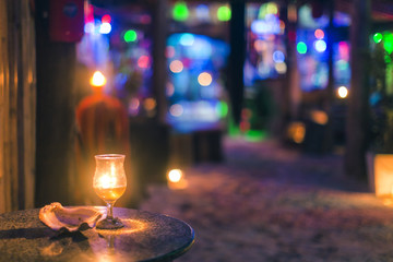 candle in glass near by shell on the table, bokeh background