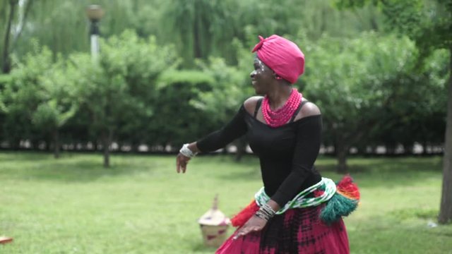 African women are dancing a folk traditional dance on a grass meadow, in traditional costumes with wicker baskets, sunny, trees' background, African costumes, traditions, African culture, tribes