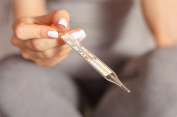 Woman sits ill in the hands of a thermometer virus flu sick