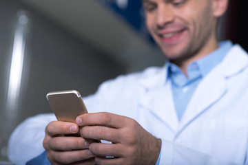Young busy practitioner sitting and using his cellphone.
