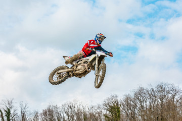 racer on a motorcycle in flight, jumps and takes off on a springboard against the sky.