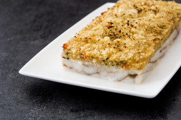 White fish casserole with cheese on black stone