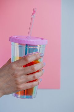Woman's hand holding a plastic cup with a drinking straw