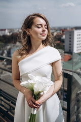 The charming bride looking at city and standing on the ballcony