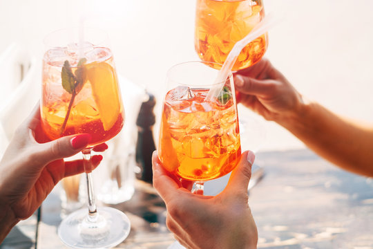Three women making a celebratory toast with aperol spritz cocktails