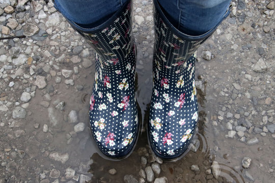 Woman Wearing Wellington Boots Standing In A Puddle Of Water