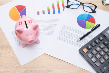 Pink piggy bank with graph and calculator on wooden desk - growing interest rate concept