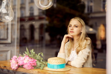 Pretty blonde girl eat her morning smoothie with flowers on the table