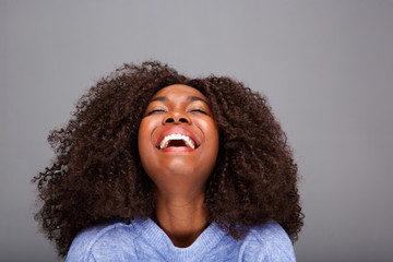 Close up young african american woman laughing on gray background