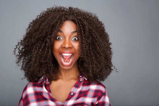 Close up excited young woman laughing with open mouth on gray background