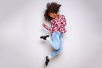 Full body cheerful young african woman jumping in air over white background