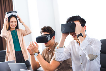 two smiling businessmen using virtual reality headsets at modern office