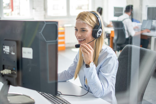 Through glass view of woman with headset working in customer support helpline center