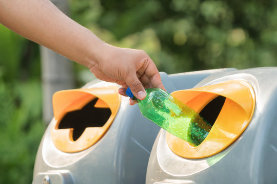 Close up hand throwing empty plastic bottle into the trash