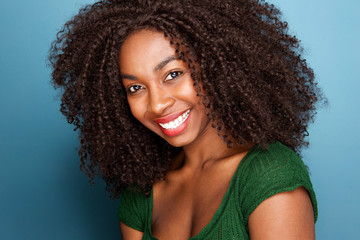 Close up beautiful young african woman with curly hair smiling on blue background