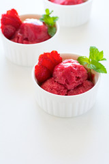 Fruit strawberry sorbet with mint in bowl on white wooden background.