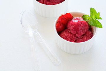 Fruit strawberry sorbet with mint in bowl on white wooden background.