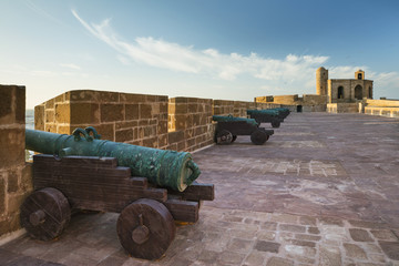 beautiful sunset with clouds in the sky above old fortress with armors in Morocco