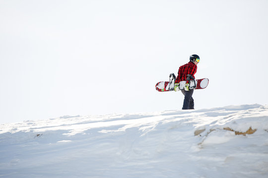Portrait of man with snowboard standing on snowy mountainside
